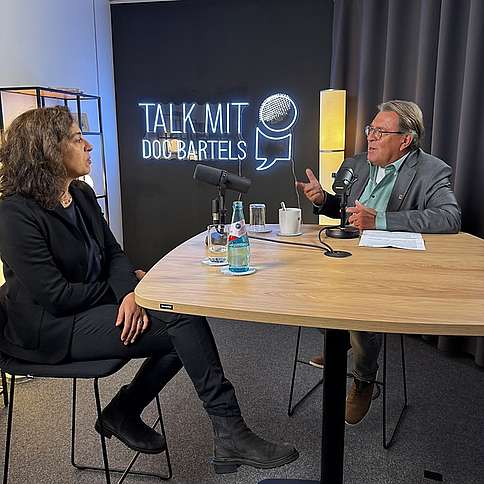 Dr. Susanne Filfil und Dr. Andreas Bartels im "Talk mit Doc Bartels" Mann höheren Alters und Frau mittleren Alters sitzend am Hochtisch im Studio