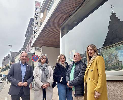 3 Frauen und 2 Männer mittleren und höheren Alters in Herbstkleidung vor Apotheken-Schaufenster